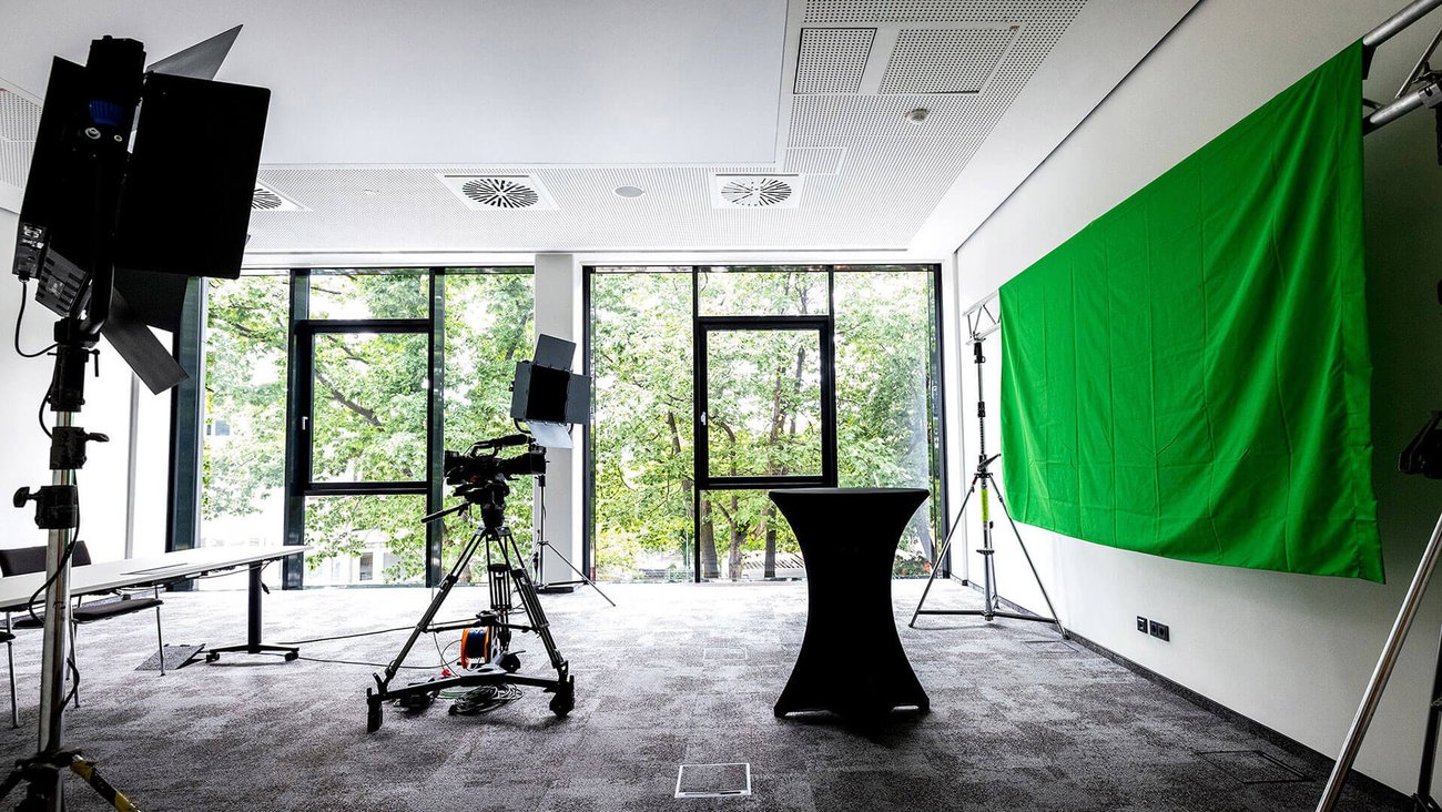 Konferenzraum ausgestattet mit Kameras, Green Screen und Stehtischen